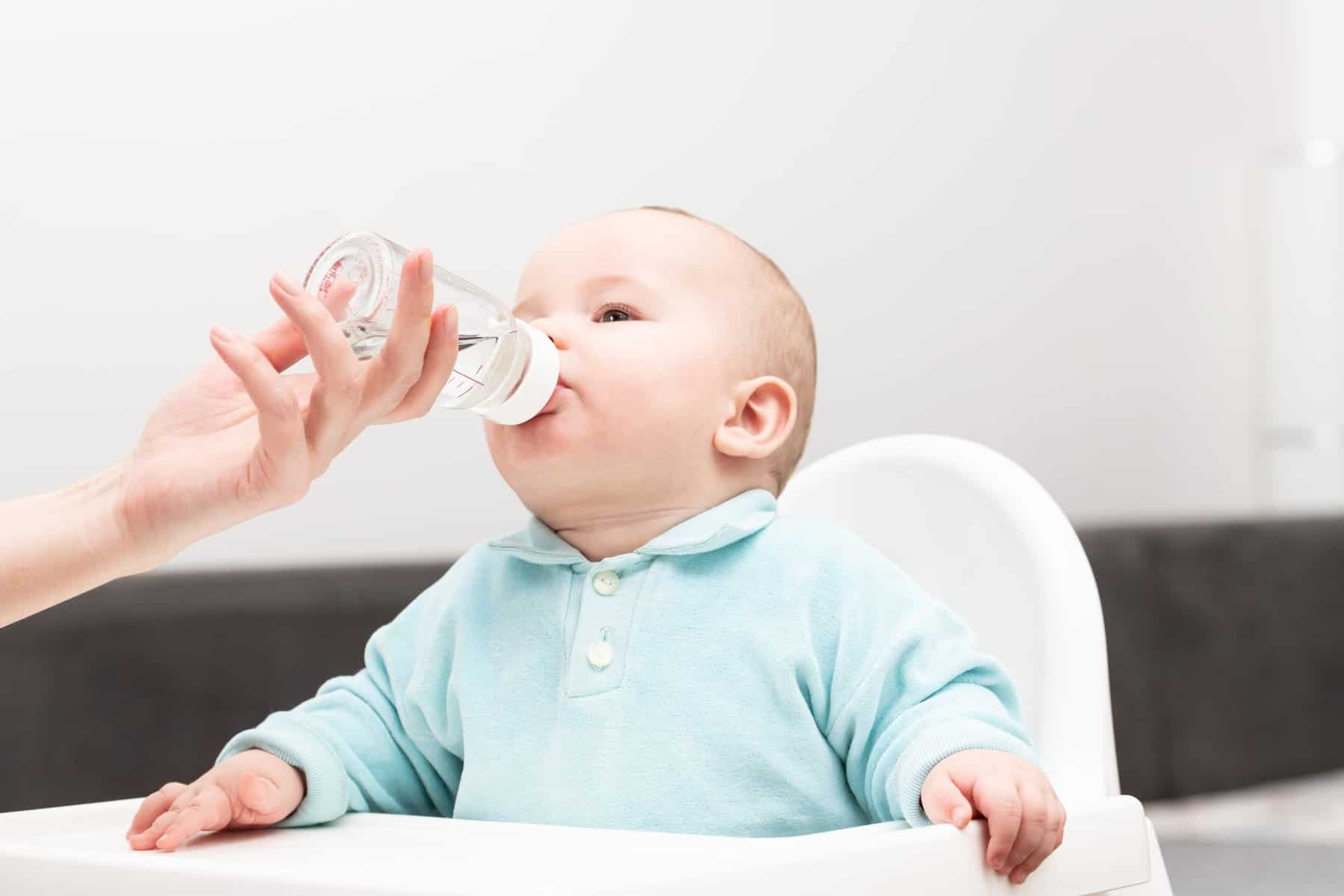 Новорожденный ребенок пить воду. Малыш-мальчик пьет воду из бутылки. Family drinking Water.